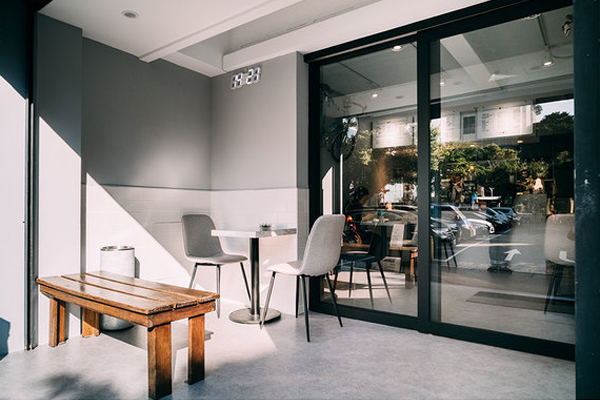 A patio with tables and chairs in front of a building with sliding glass doors.
