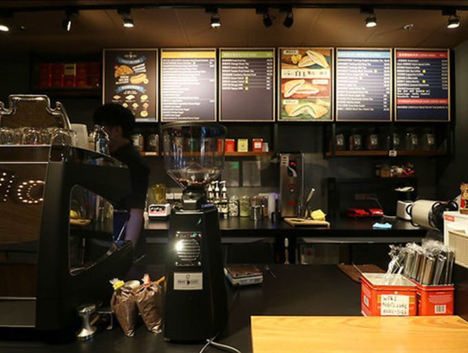 A man is standing behind a counter in a coffee shop.