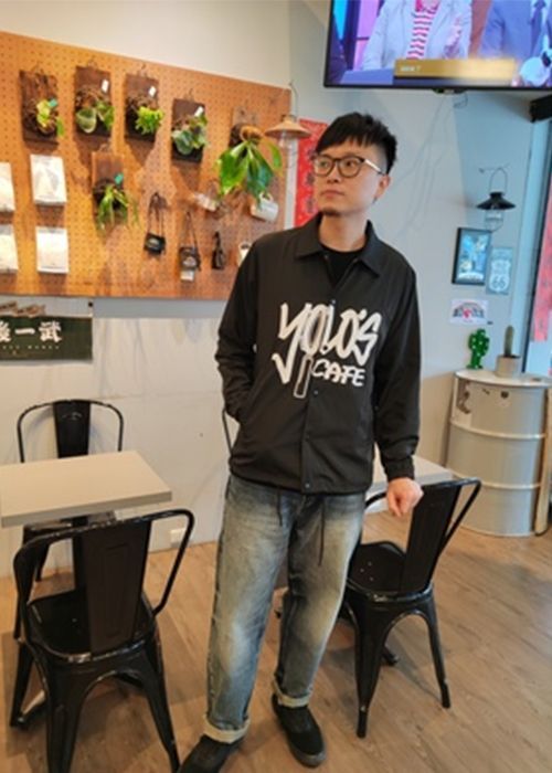 A man is standing in a room with tables and chairs.