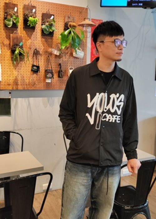 A man wearing a black jacket that says yolo 's cafe