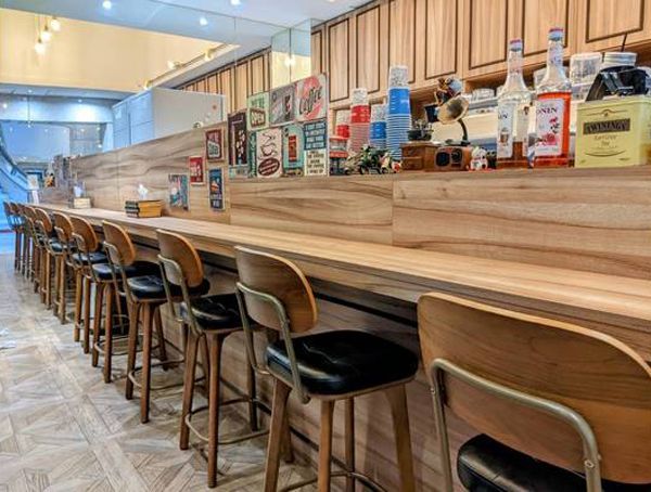 A restaurant with a long wooden counter and stools.