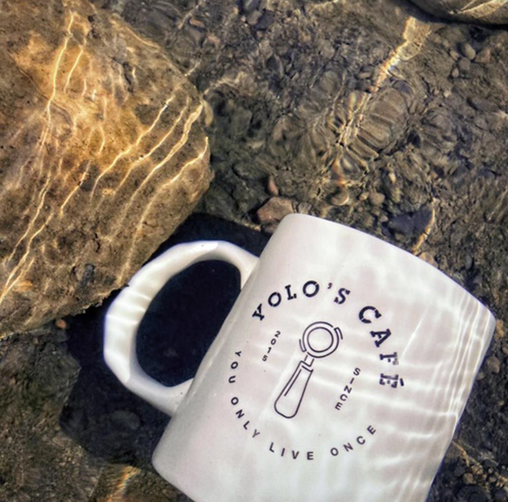 A mug that says yolo 's cafe on it