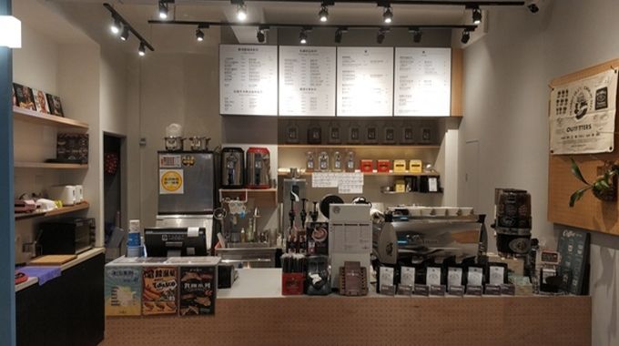 A coffee shop with a counter and a menu on the wall.