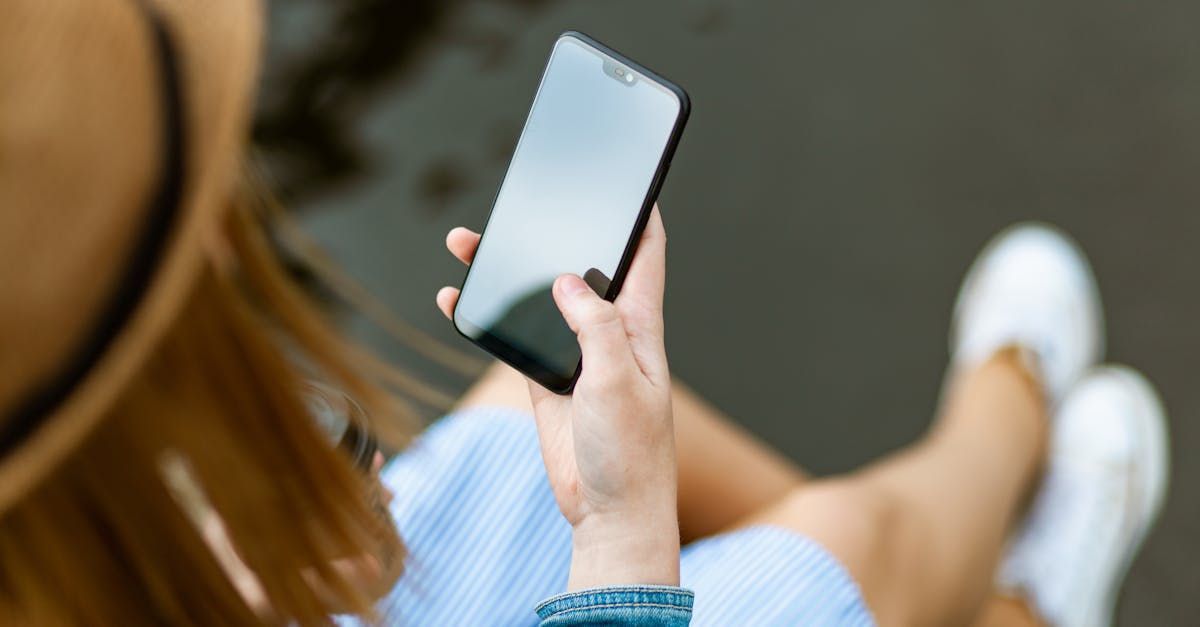 A woman is sitting on a bench holding a cell phone in her hand.