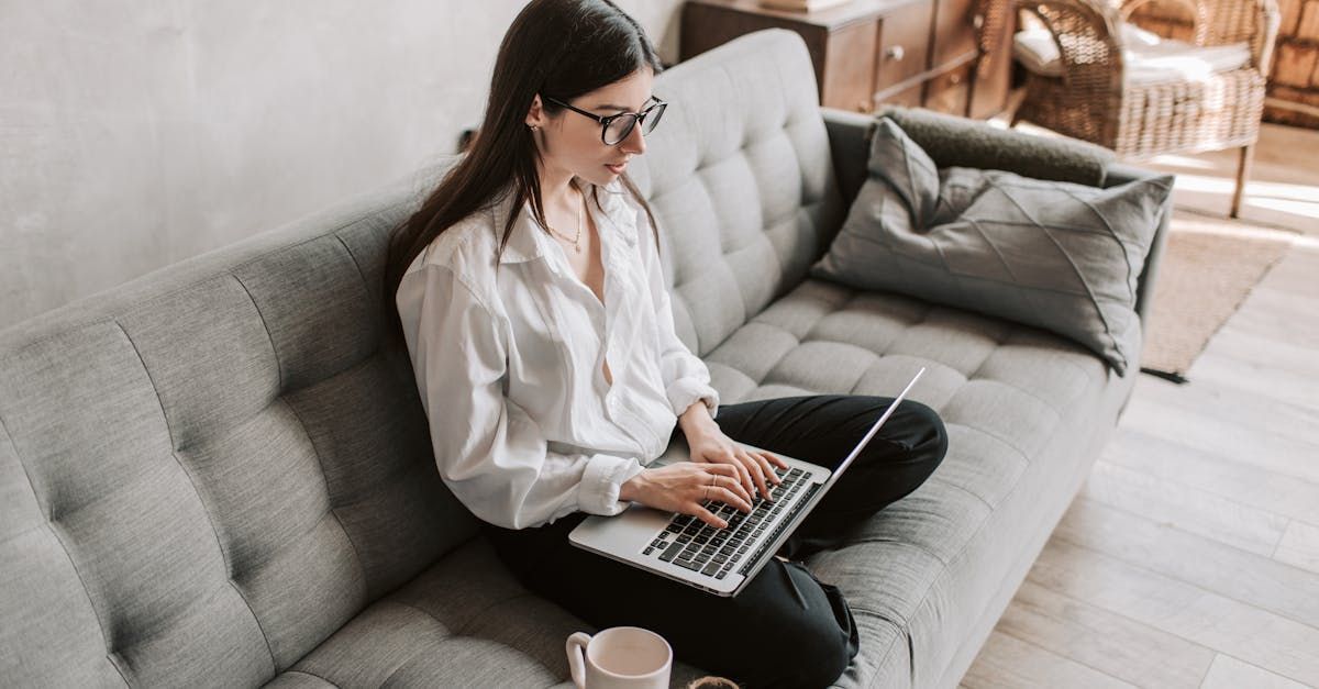 A woman is sitting on a couch using a laptop computer.