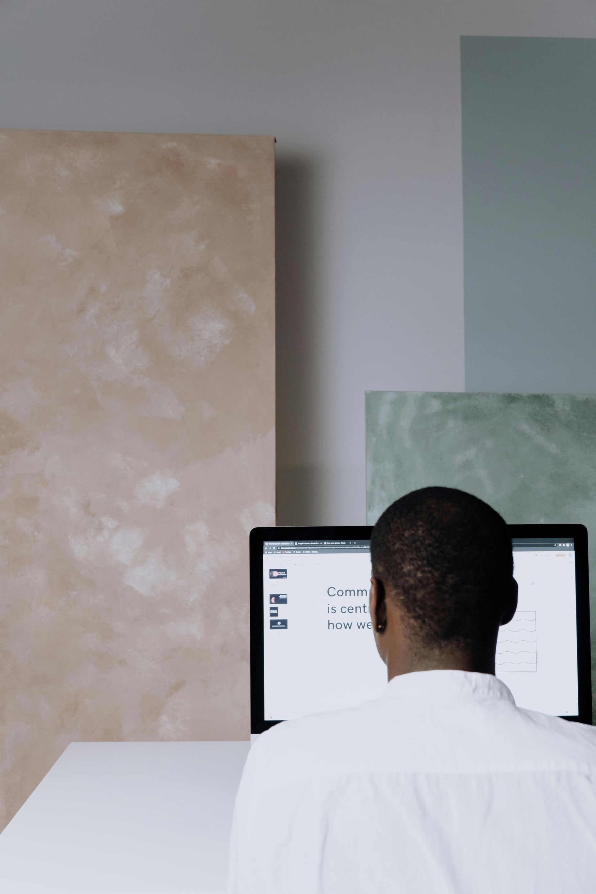 A man is sitting at a desk looking at a computer screen.