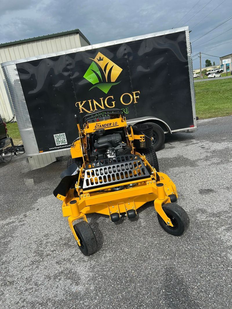 Yellow lawnmower in front of black trailer with 