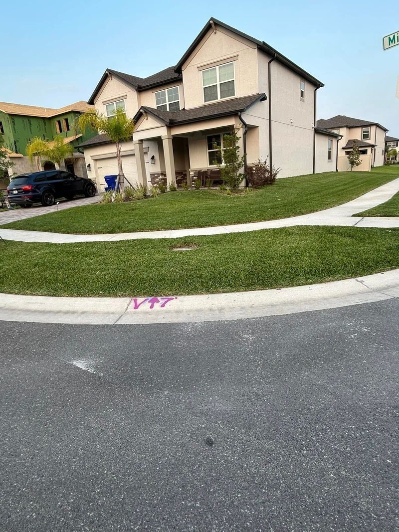 Two-story beige house with green lawn on a sunny day. 