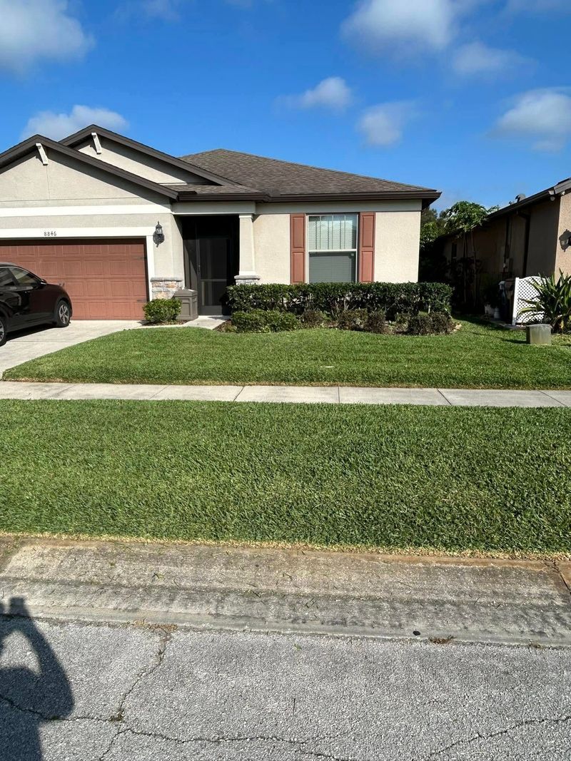 Suburban home with brown roof, garage, and landscaping on a sunny day.