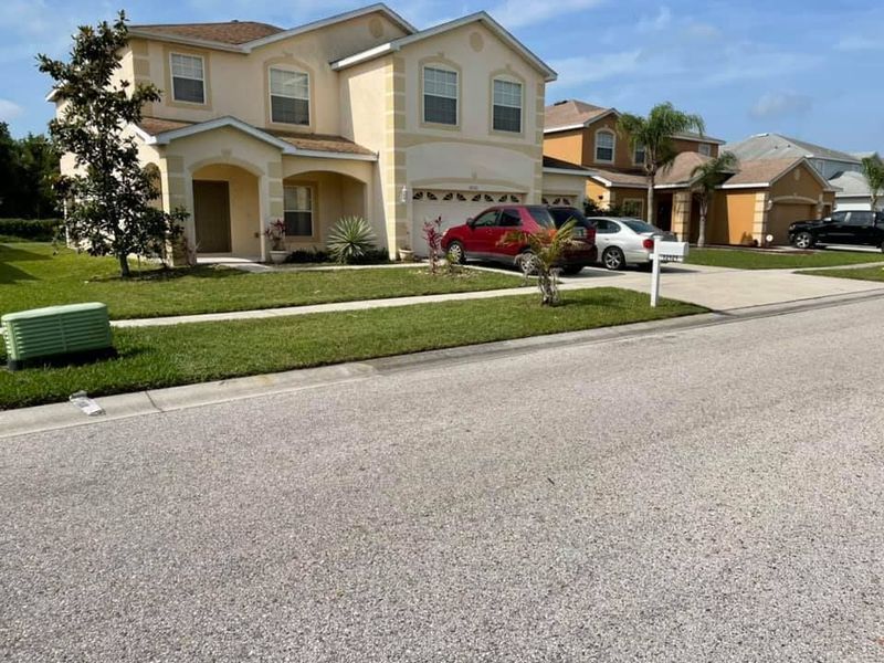Suburban houses on a street, vehicles parked. 