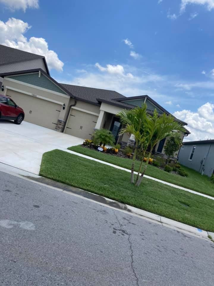 Suburban home with green lawn, driveway, and blue sky with clouds.