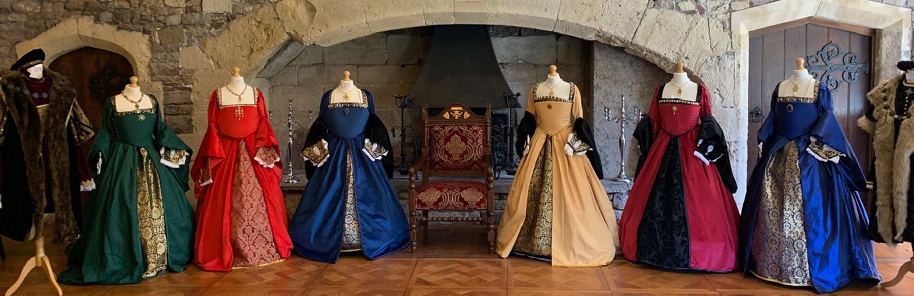 A row of Tudor dresses on mannequins in a room.