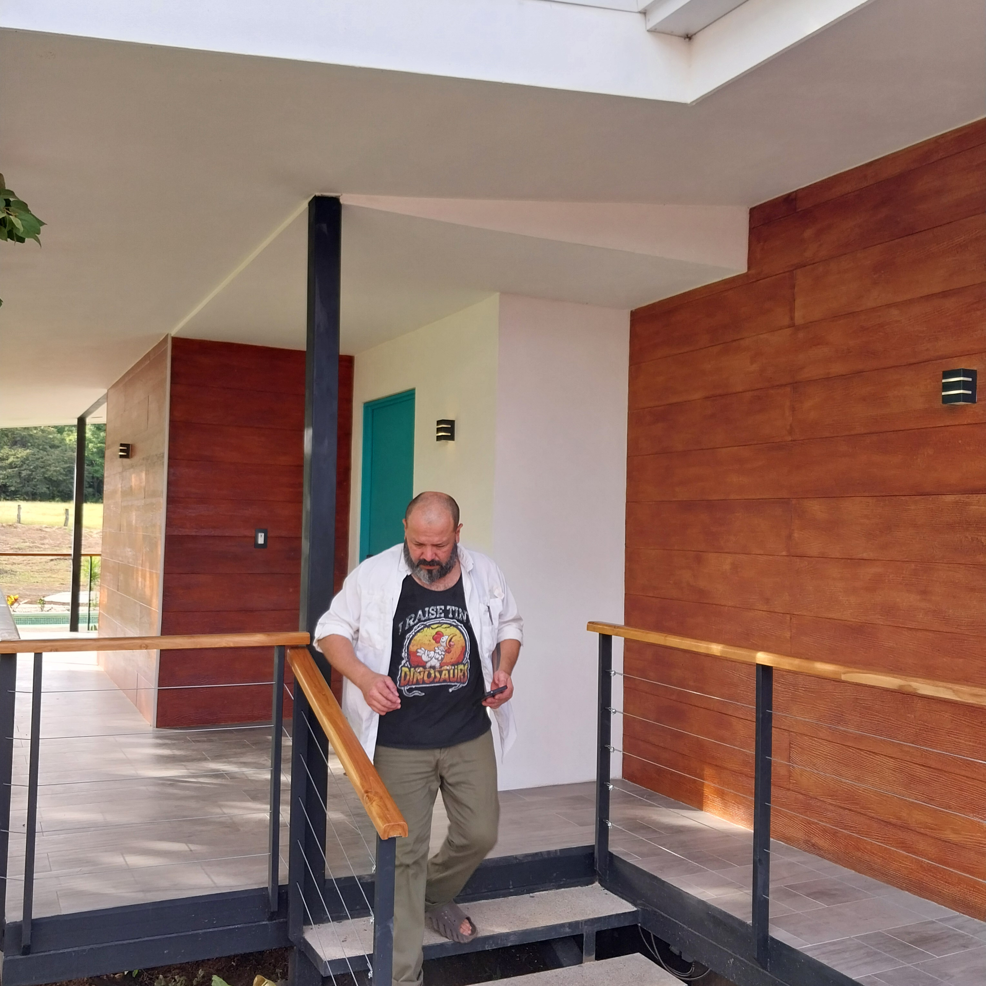 Man descending stairs from a modern building with wood paneling and a turquoise door.