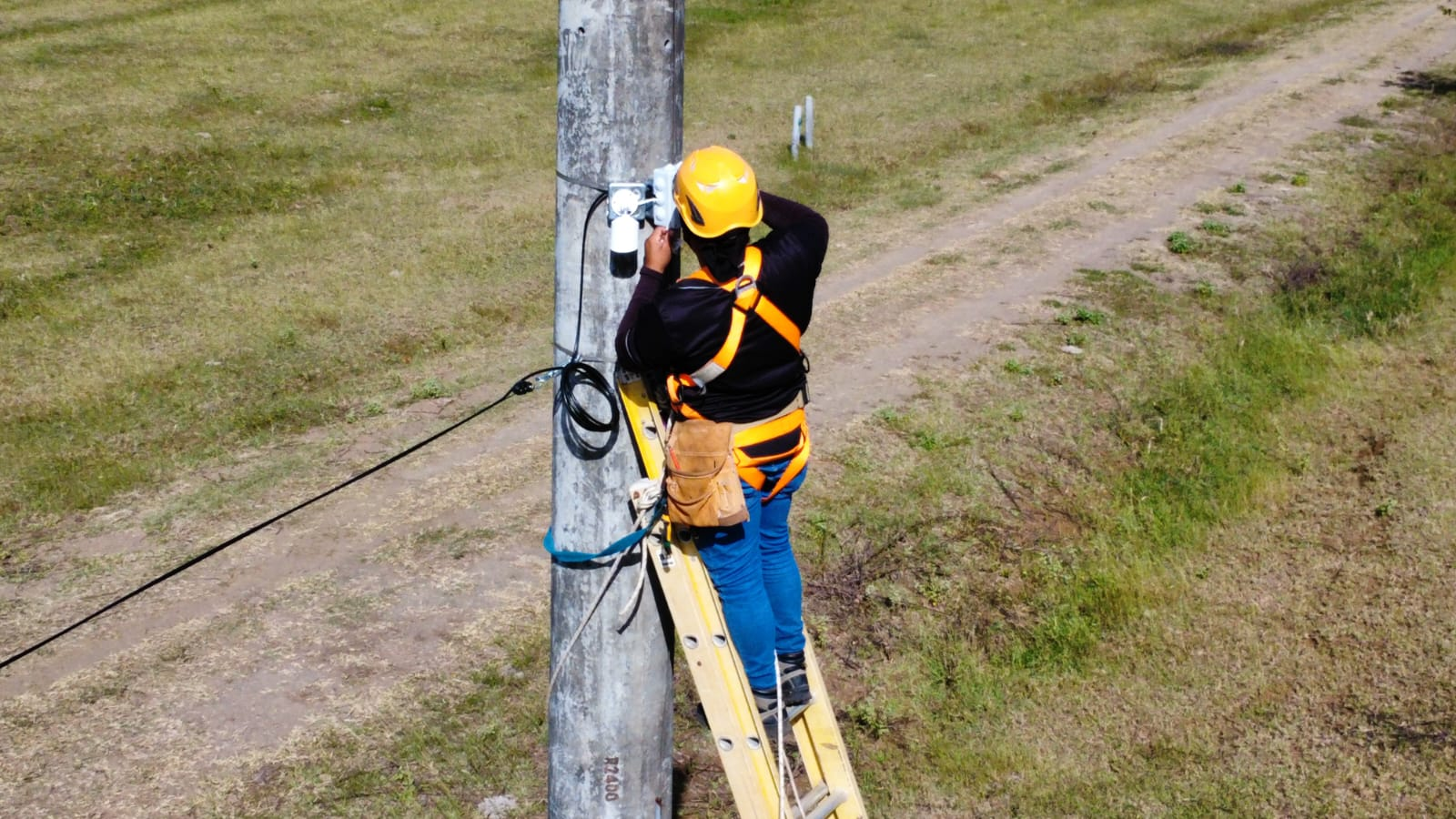 Lineman in safety gear working on a utility pole.