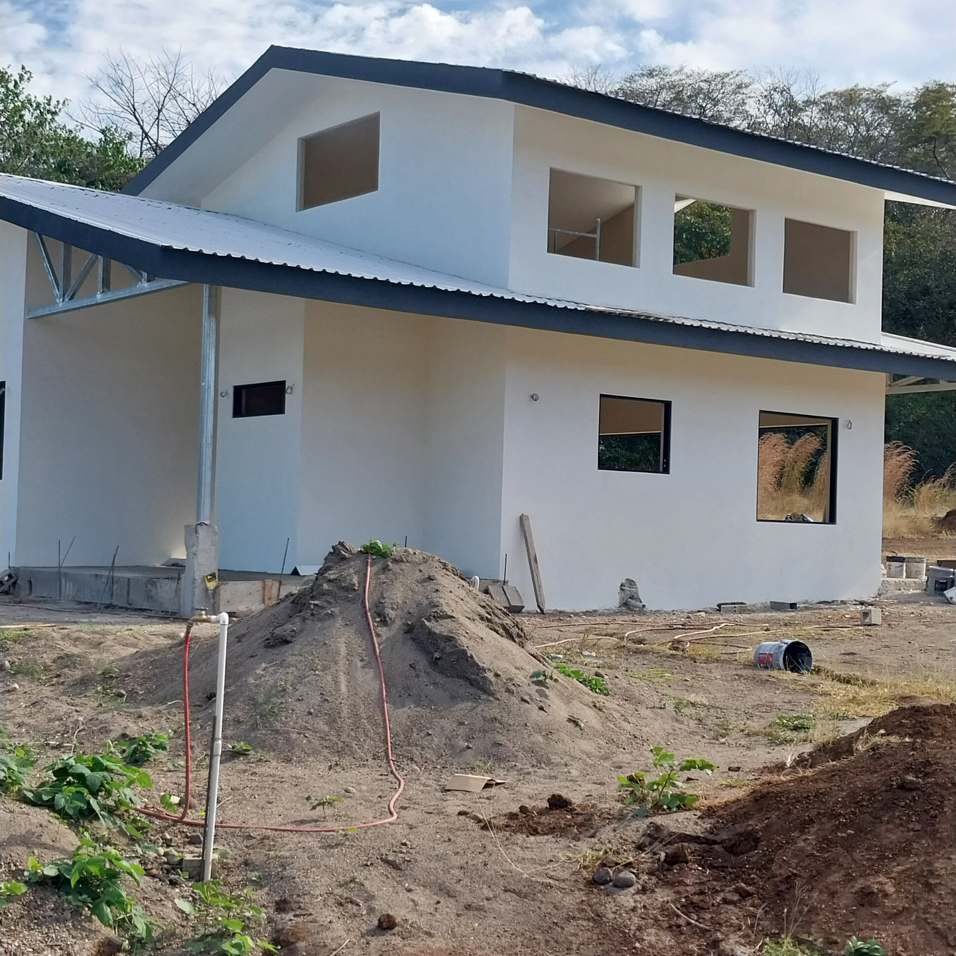 White house under construction, with open window frames and metal roof.