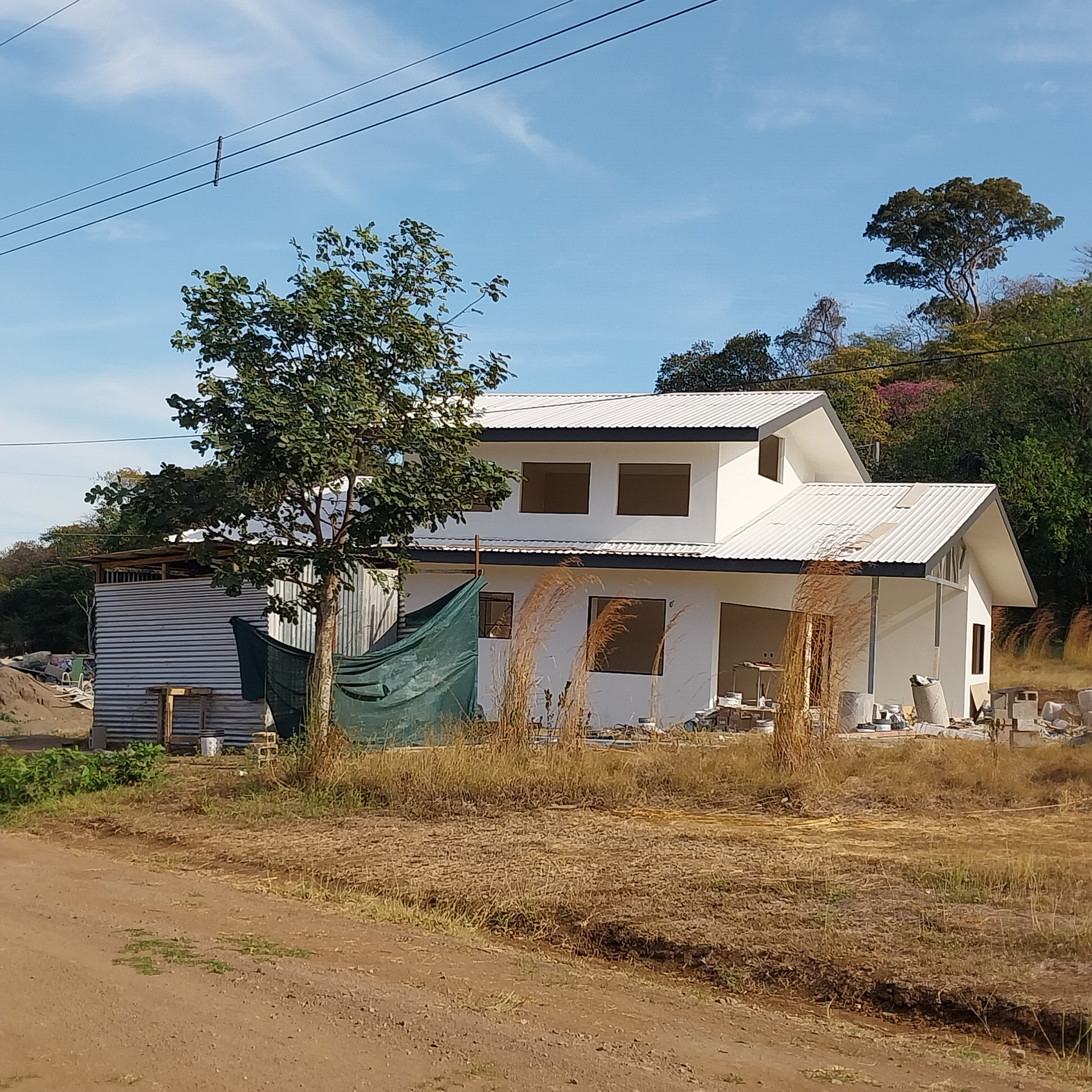 White house under construction, brown and tan landscape, blue sky.