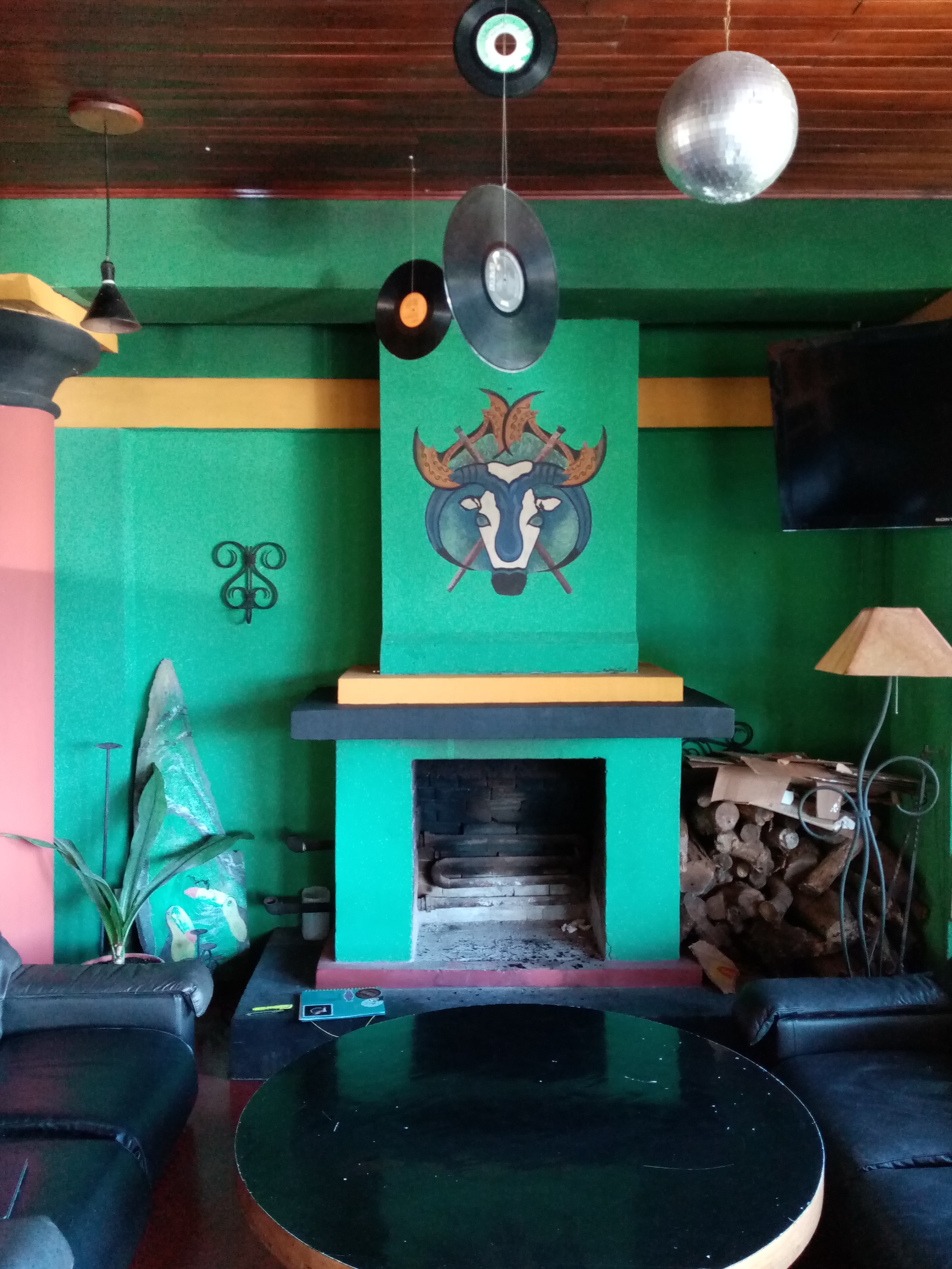 A colorful living room with a fireplace, vinyl records, a bull painting, and a black round table.