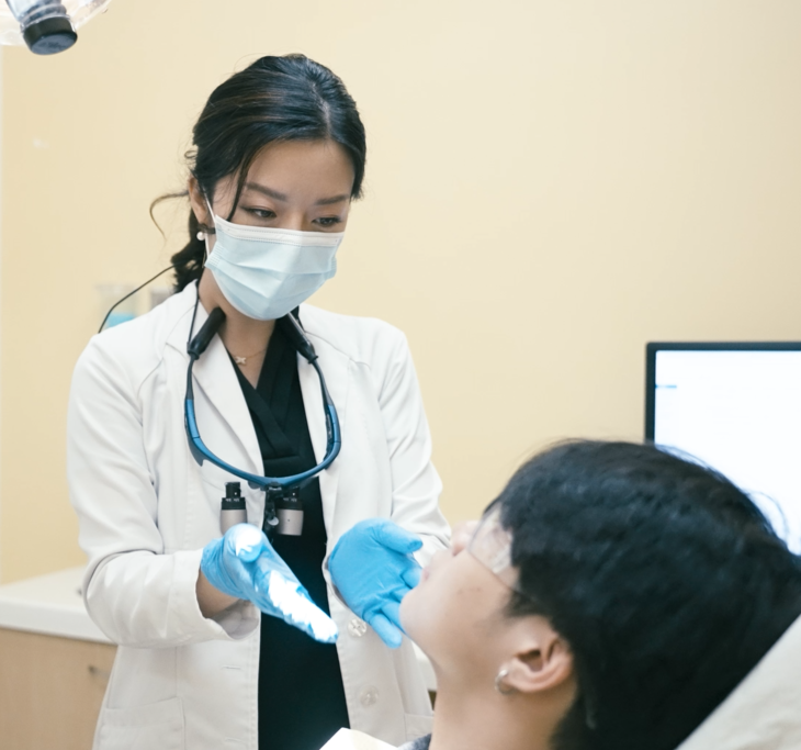 A doctor wearing a mask and blue gloves examines a patient