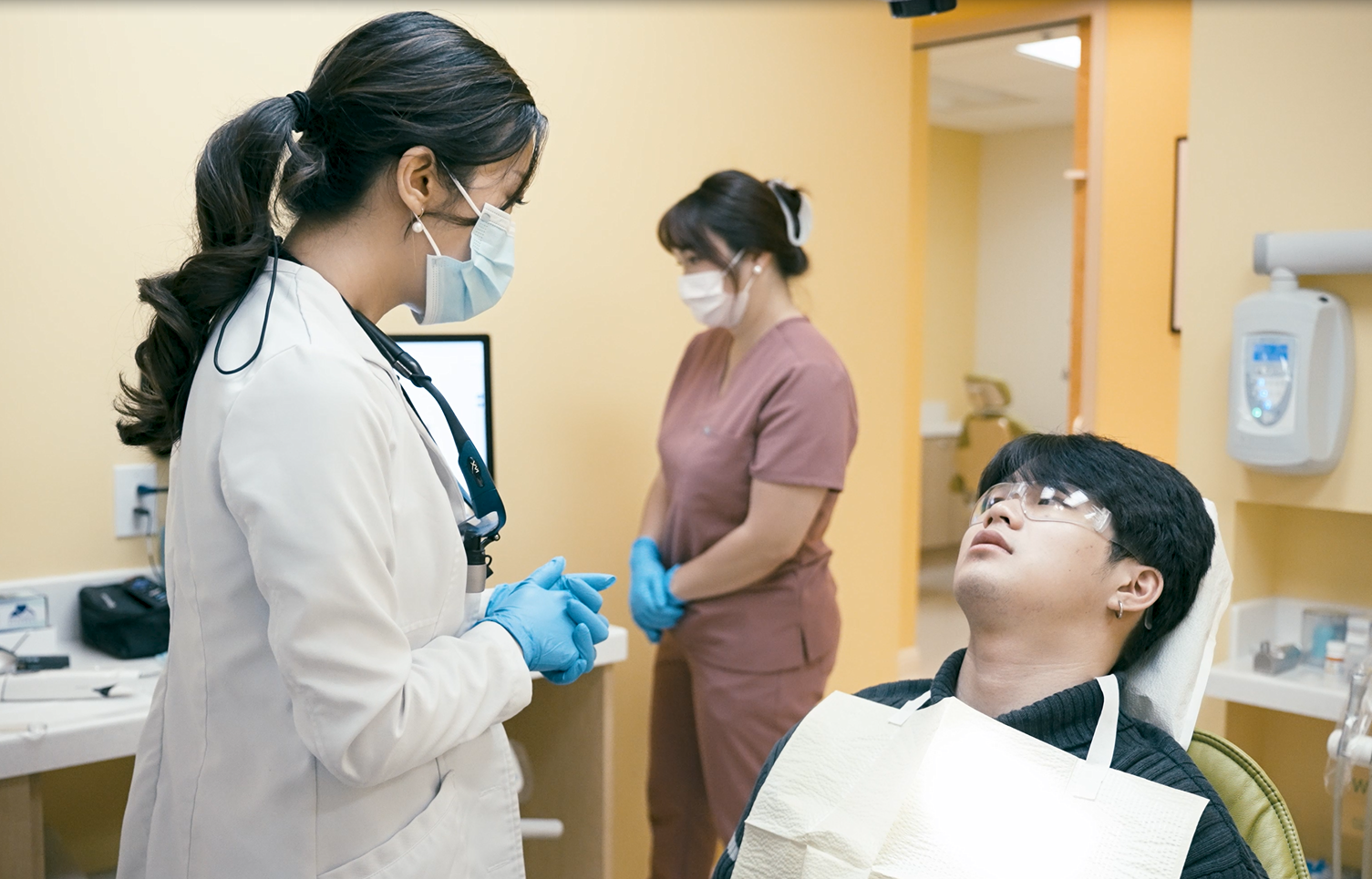 A dentist is examining a patient 's teeth in a dental office.