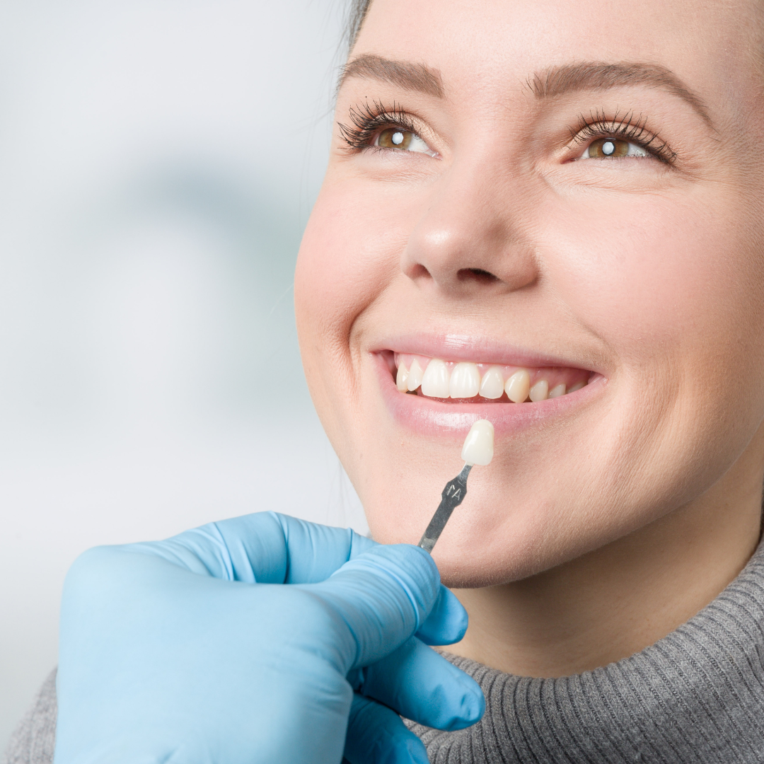 Dentist in blue scrubs, mask, and face shield working on a patient's teeth.