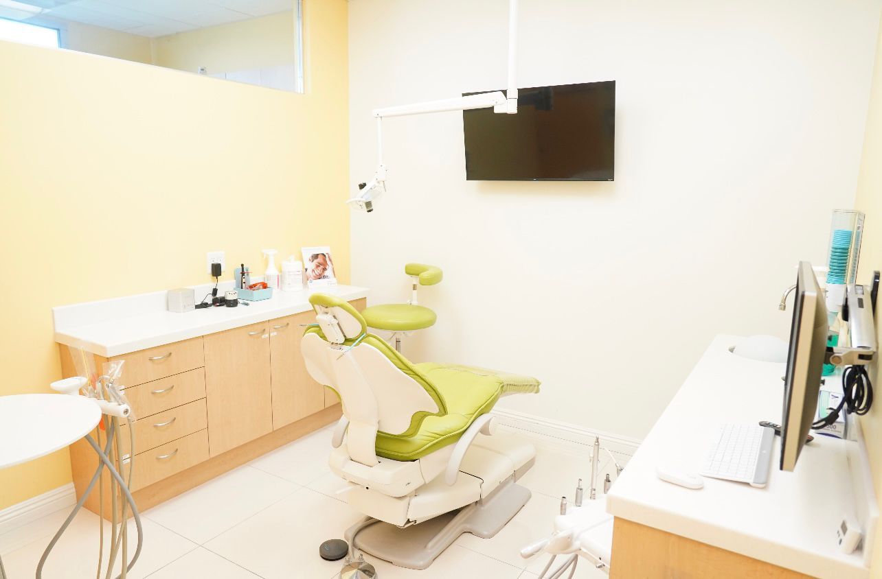 A dental office with a green dental chair and a flat screen tv.