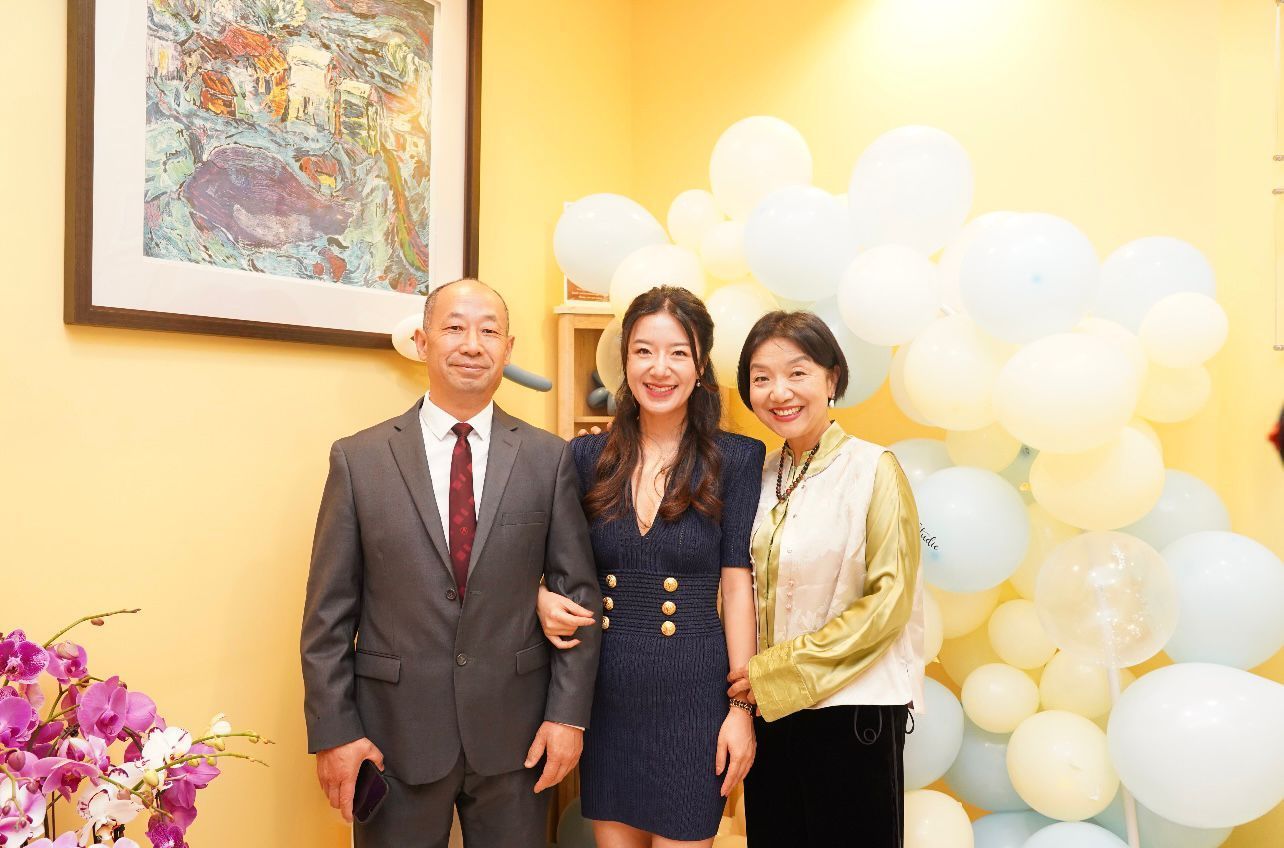A man in a suit and tie is standing next to a woman and a woman in a dress.