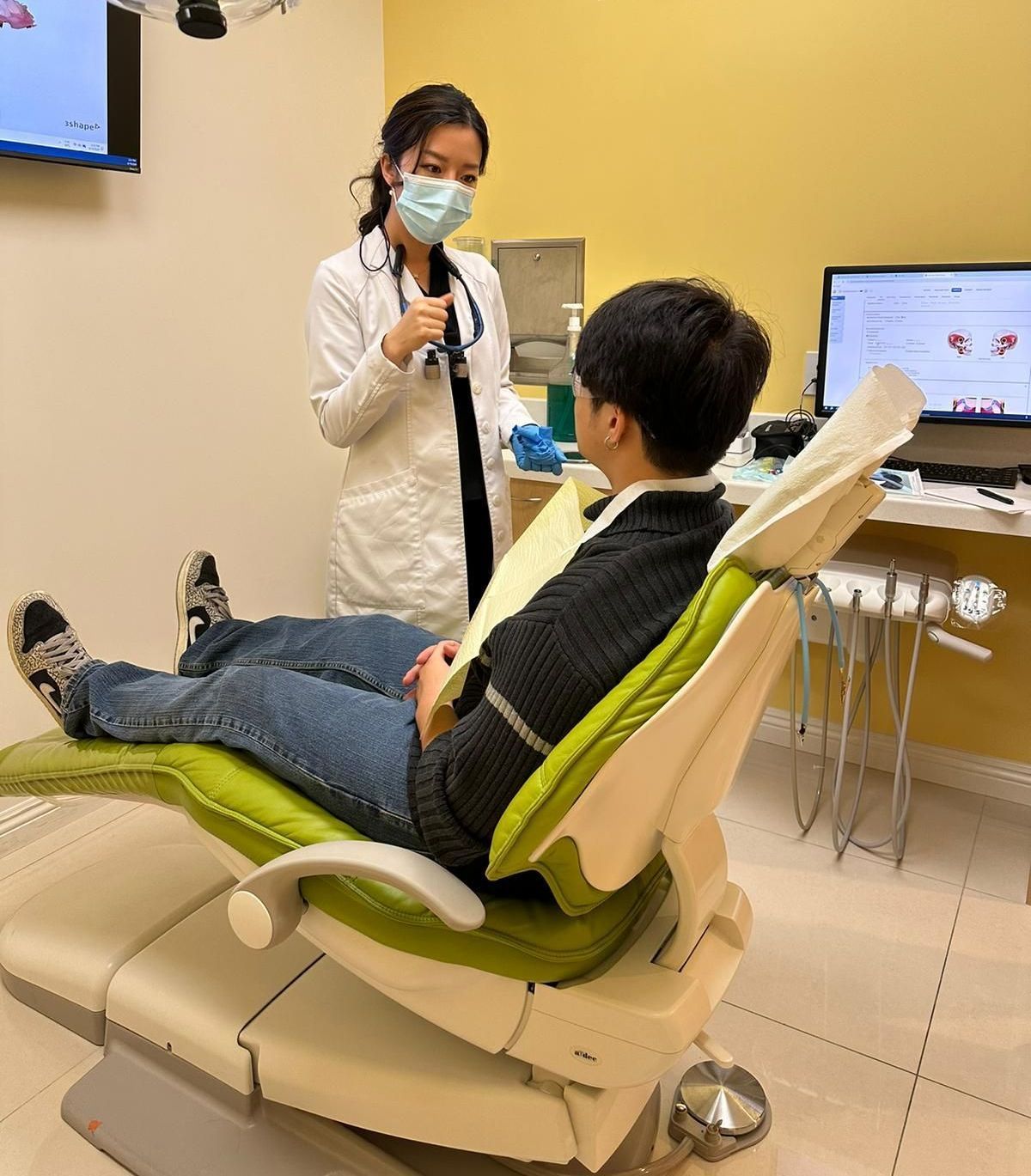 A man is sitting in a dental chair talking to a female doctor