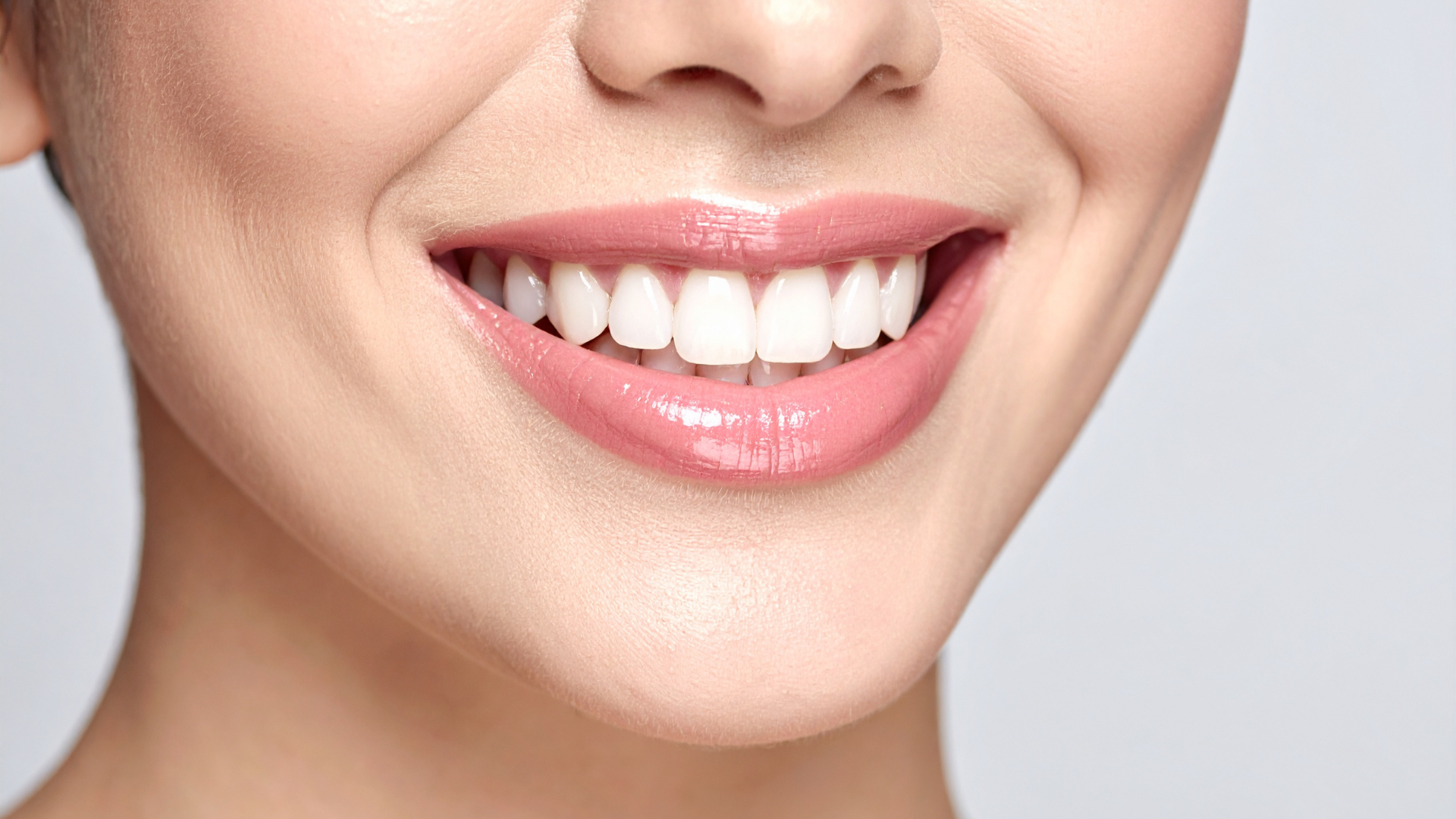 Smiling mouth with full, pink lips and white, even teeth.