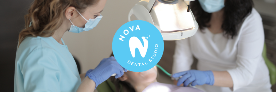 Two dental professionals, wearing masks and gloves, treat a patient at a dental studio.
