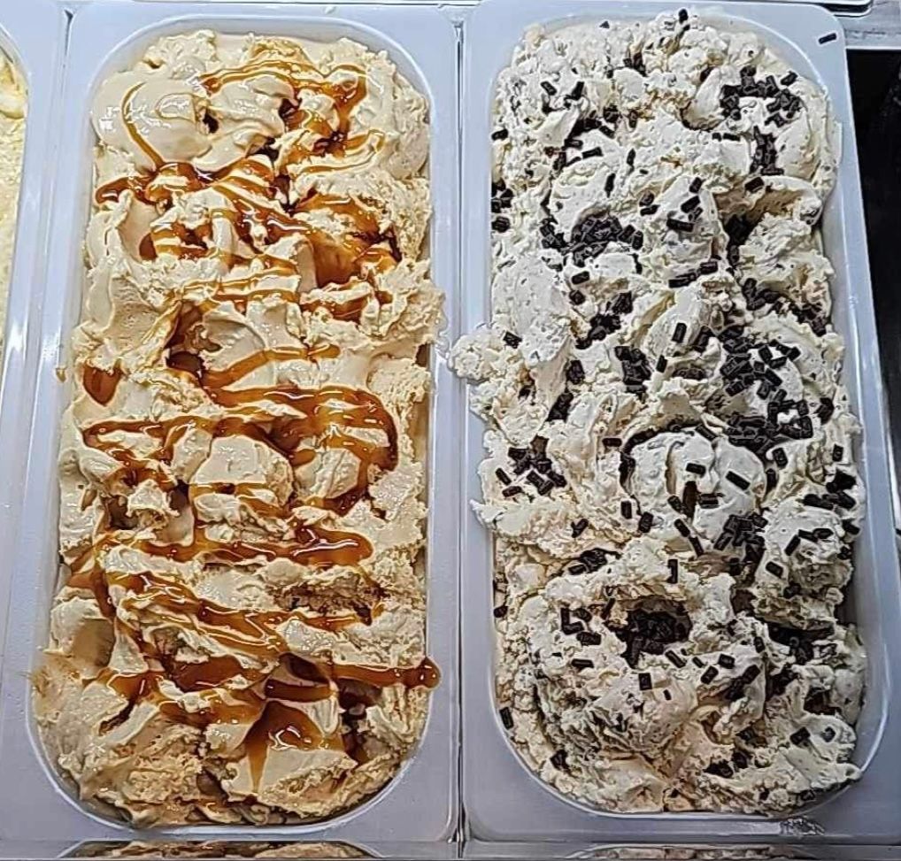 Two containers of gelato with caramel and chocolate sprinkles on top.