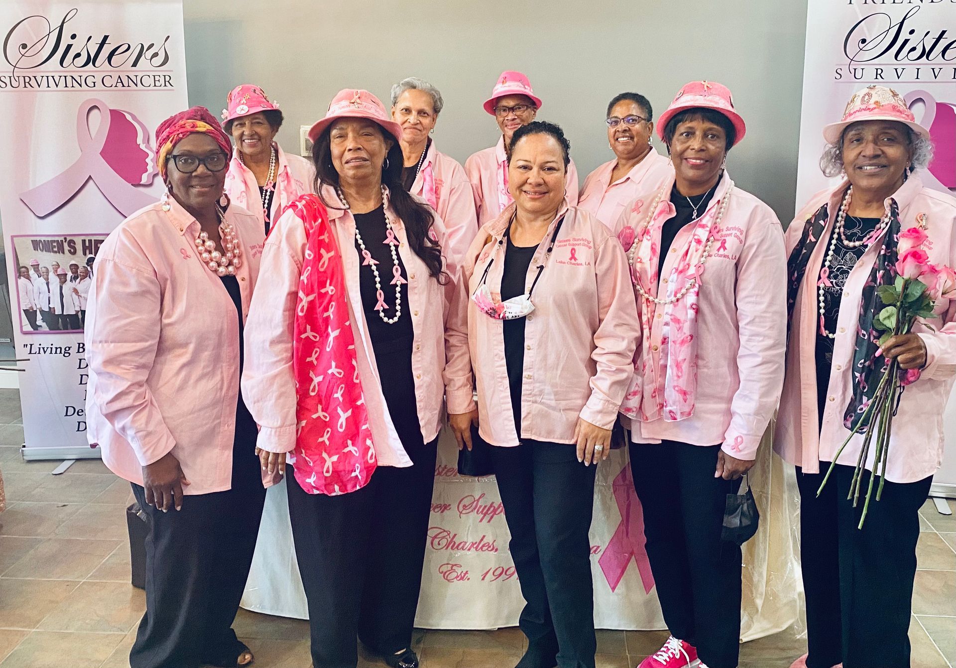 A group of women wearing pink shirts and hats are posing for a picture.