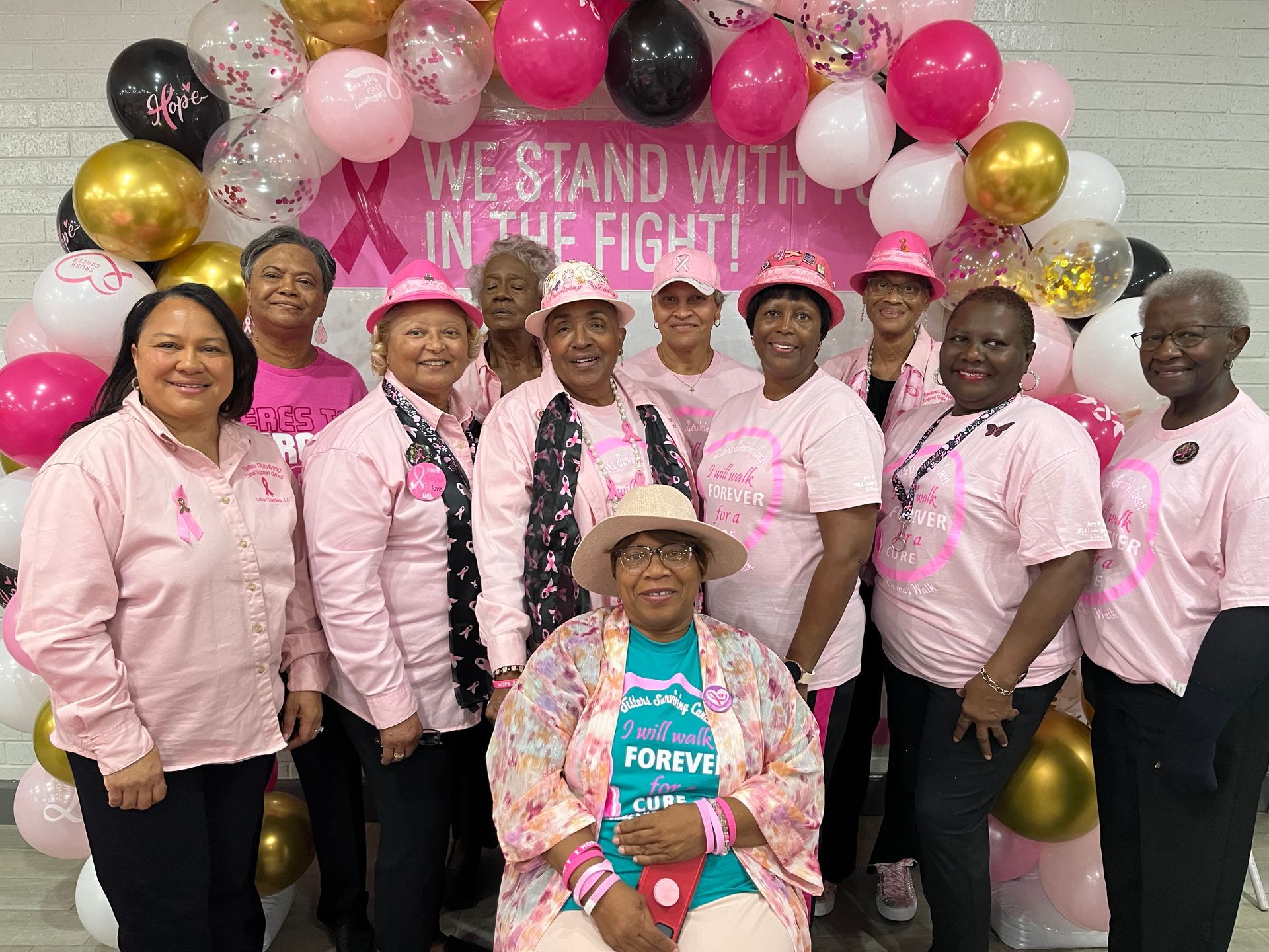 A group of women are posing for a picture in front of balloons.
