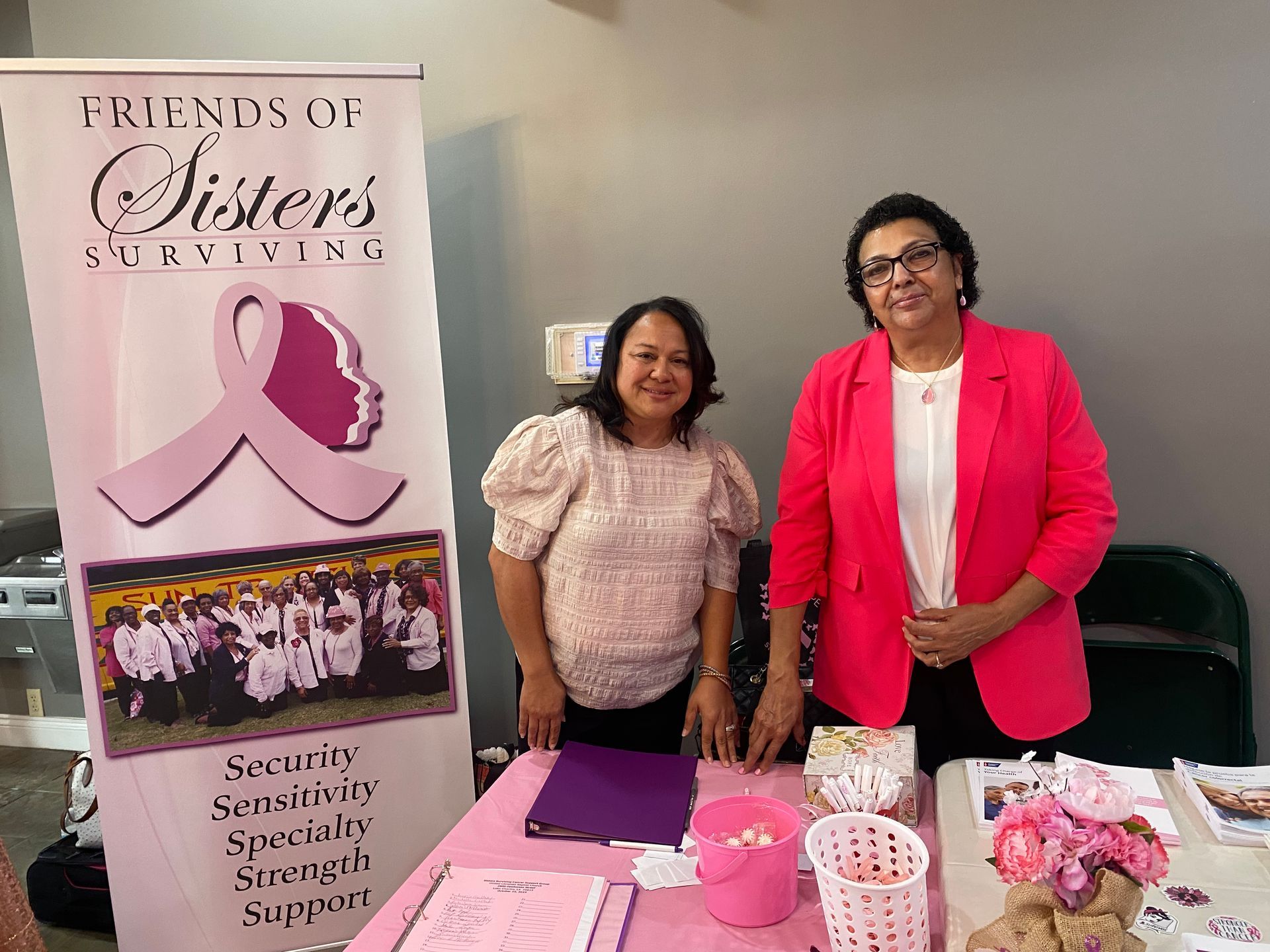 Two women are standing in front of a sign that says `` friends of sisters surviving ''.