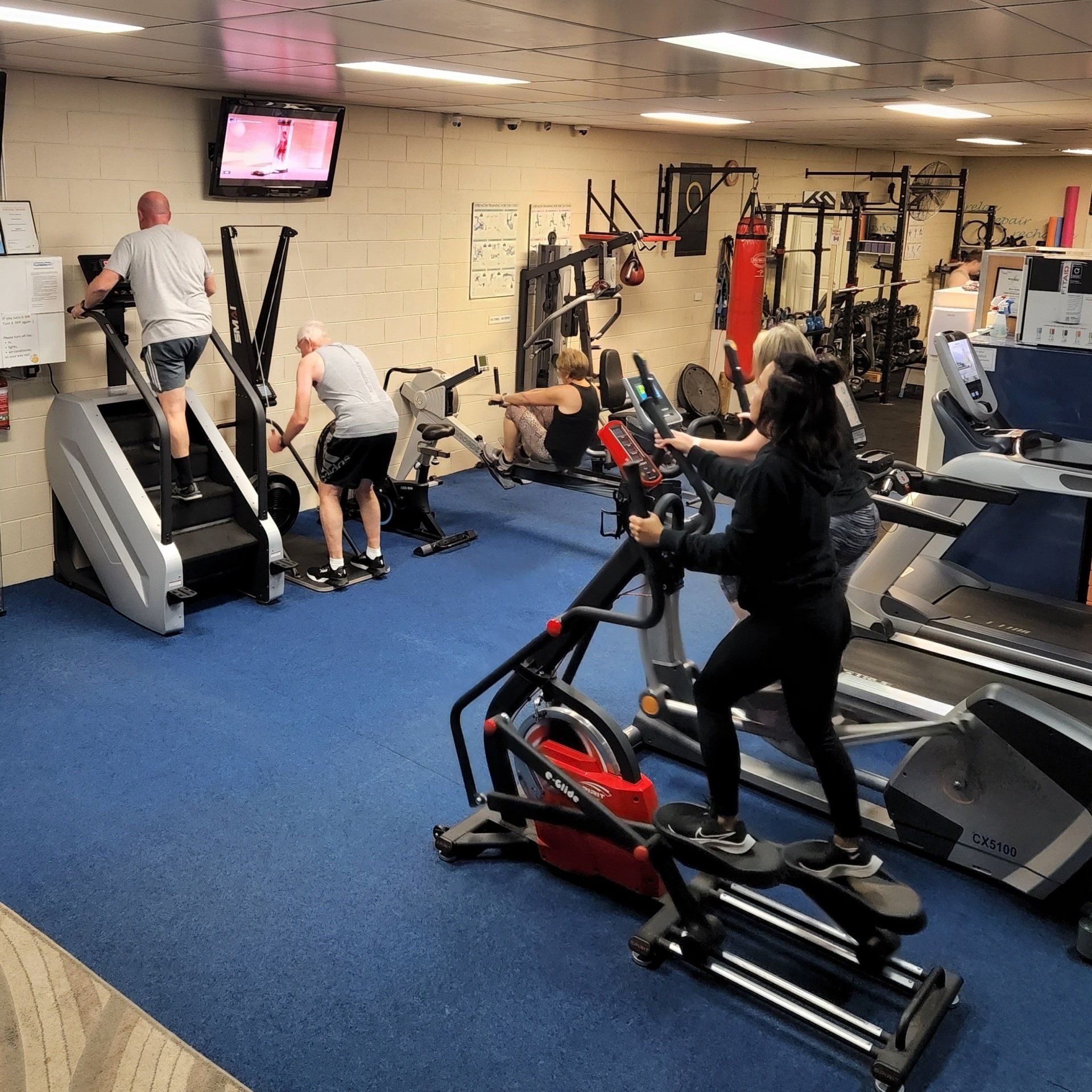 Young People - group of women and men - doing sport biking in the gym for fitness