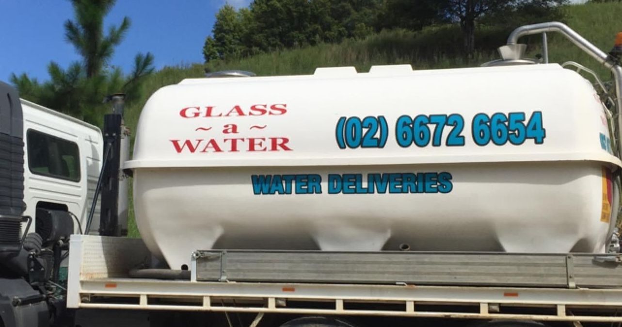 A glass and water truck is parked on the side of the road