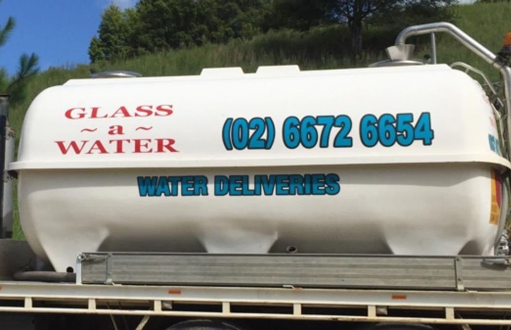 A glass water delivery truck is parked on the side of the road