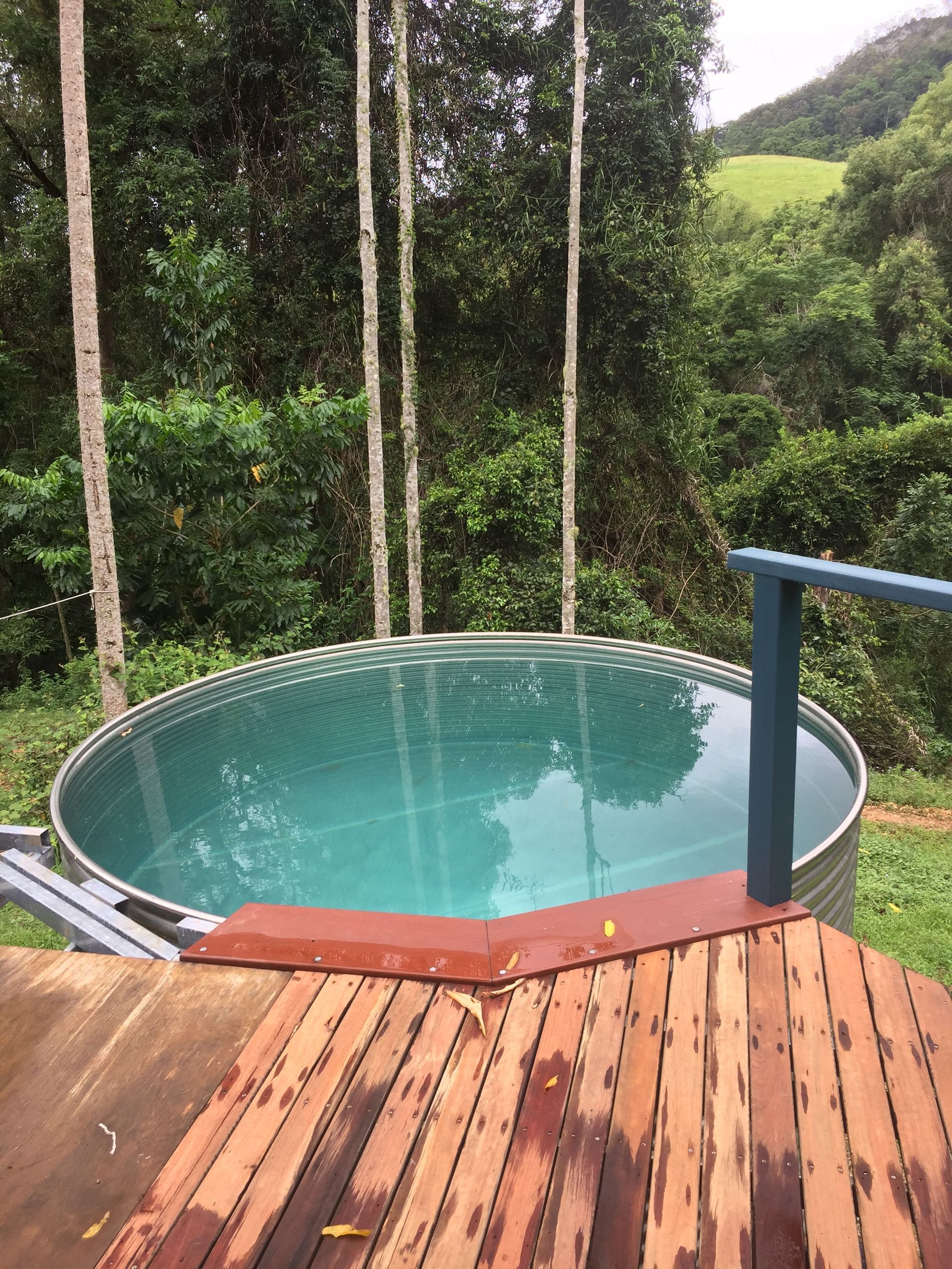 A large swimming pool is sitting on top of a wooden deck.