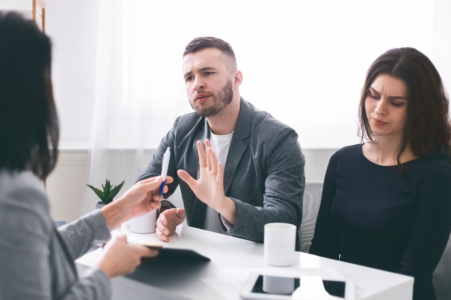 Semi-truck and trailer crashed off road. People stand near wreckage, green field, blue sky.