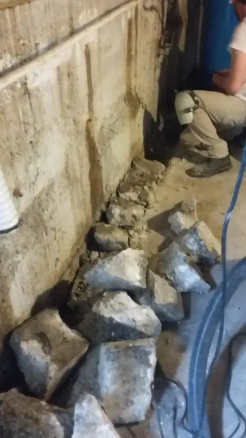 A man is sitting on the floor next to a pile of rocks.