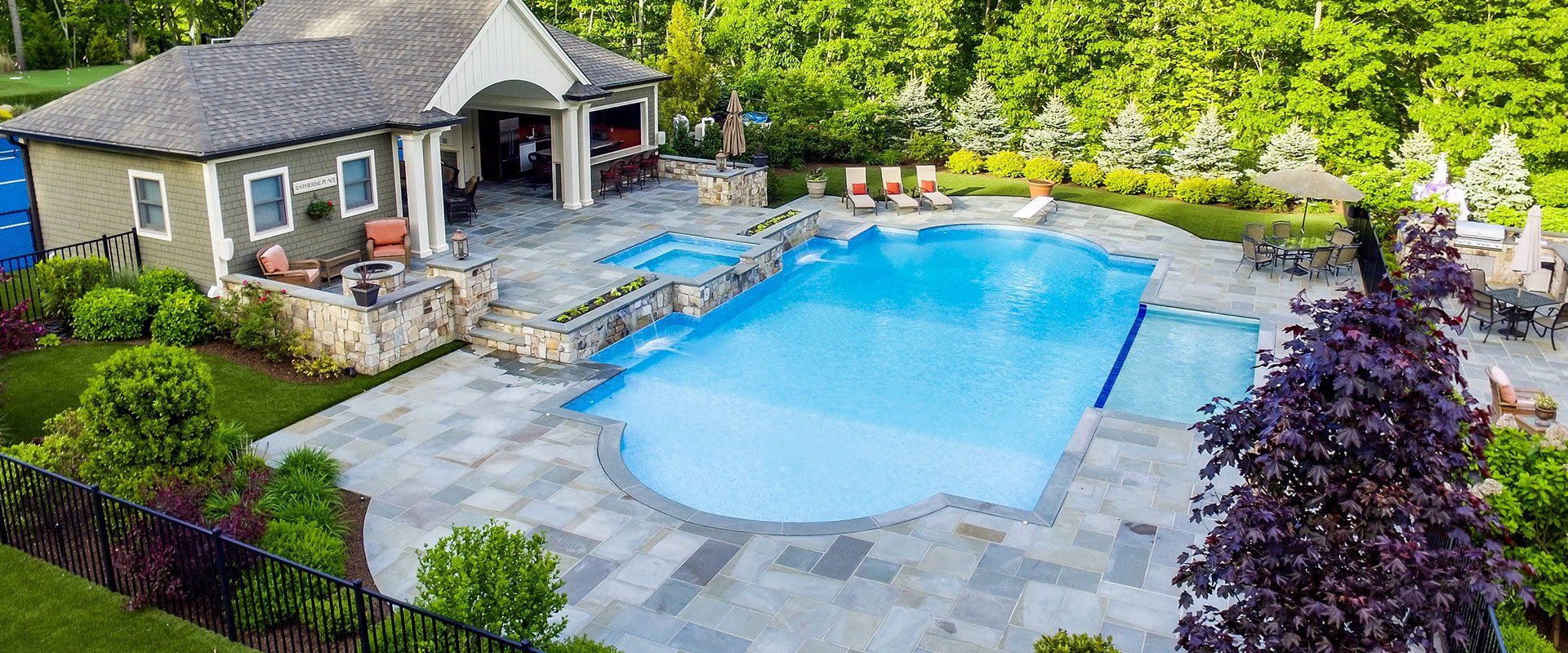 An aerial view of a large swimming pool in a backyard with a house in the background.