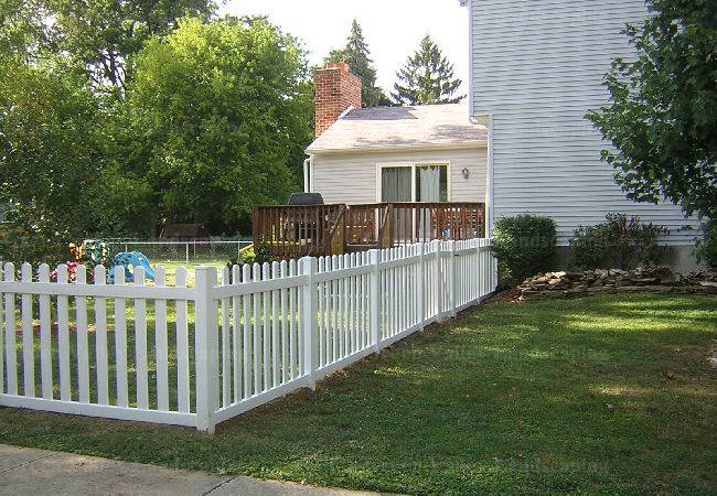 A white picket fence is in front of a house