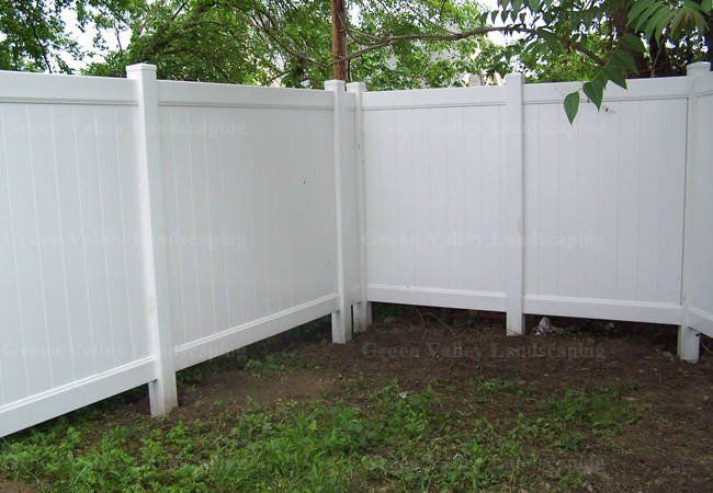 A white fence is surrounded by grass and trees