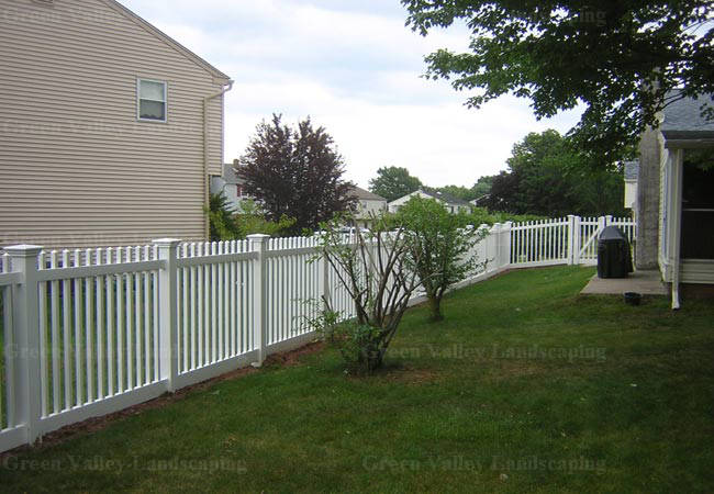 A white picket fence surrounds a lush green yard