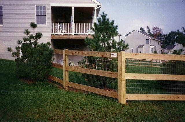 A house with a screened in porch and a wooden fence in front of it