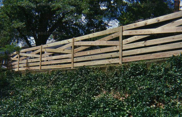 A wooden fence is sitting on top of a hill surrounded by trees.