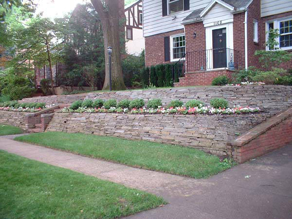 A brick house with a stone wall in front of it.