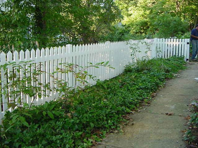 A man is standing next to a white picket fence.