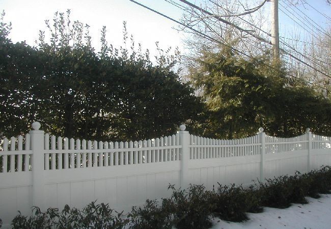 A white picket fence with trees in the background