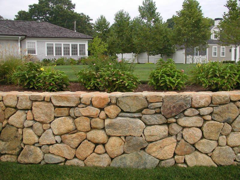 A stone wall with a house in the background