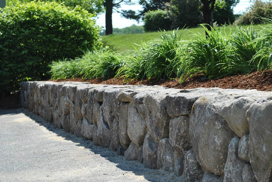 A stone wall surrounds a lush green field